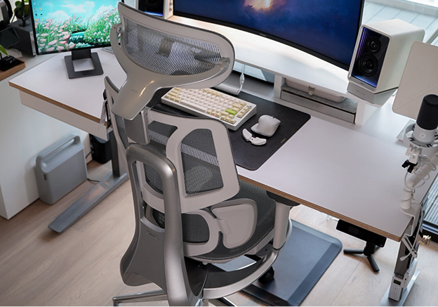 Ergonomic chair in front of a computer desk with multiple monitors and office equipment.